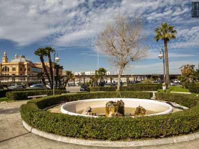 ...al centro del quale si apre un piccolo giardinetto intitolato a Fabrizio De Andr�. Qui, tra palme e siepi, trovano posto alcune panchine in pietra poste attorno a una fontana circolare zampillante